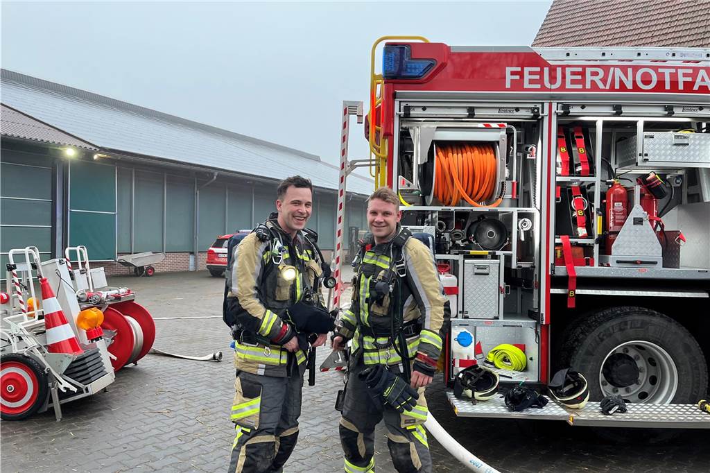 Feuer auf Bauernhof: Landwirt bekämpft Brand mit Feuerlöscher Zwei Feuerwehrmänner mit Atemschutzgeräten auf dem Rücken.