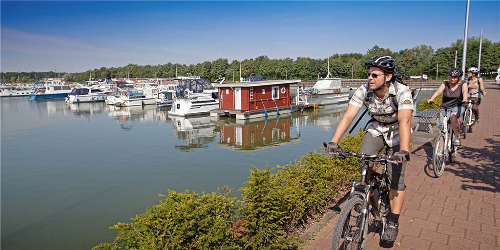 Der Weg ist das Ziel - Die schönsten Radstrecken für Urlaub in NRW Radfahrer fahren an einem kleinen Hafen vorbei.