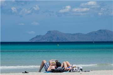 Urlauber liegen am Strand an der Platja de Muro im Norden der Mittelmeerinsel Mallorca. Foto: Julian Stratenschulte