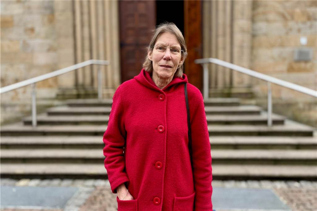 Ursula Kathriner steht, in einen roten Mantel gekleidet, vor der Lambertuskirche in Castrop-Rauxel.