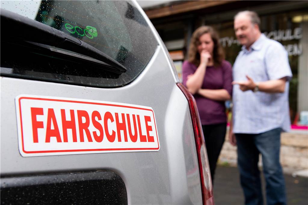 Durchfallquote bei Führerscheinprüfung erreicht in Haltern Rekordniveau Ein Auto mit einem "Fahrschule"-Aufkleber. Daneben erklärt ein Fahrlehrer einer Schülerin etwas über das Auto.