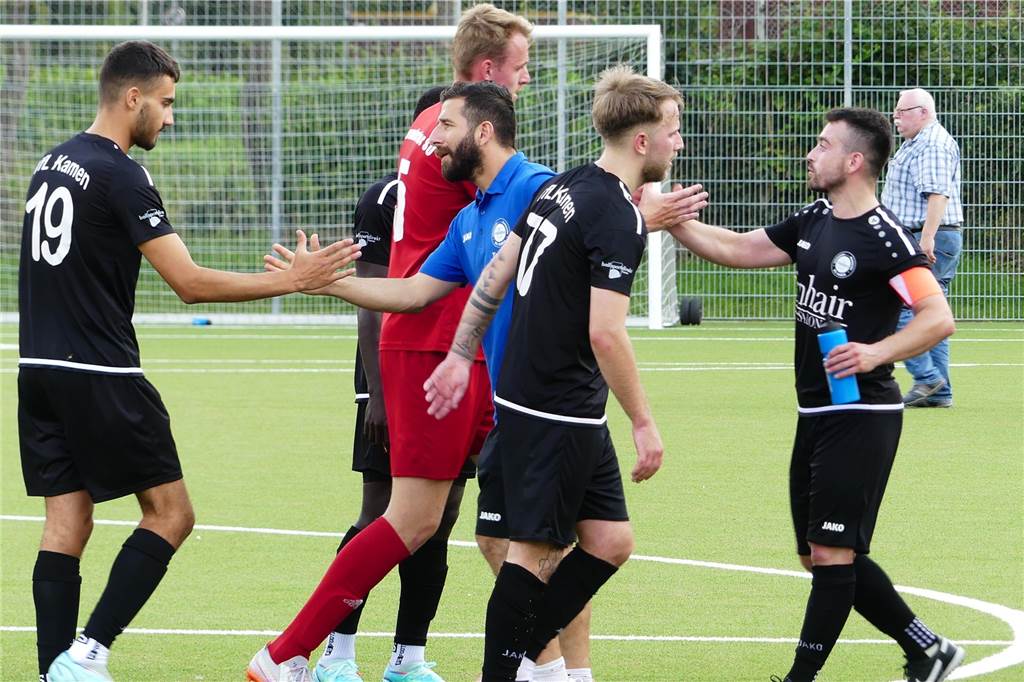 Vizemeister VfL Kamen holt Big Points, Aufsteiger hält aber gut mit VfL-Trainer Mehmet Kara klatscht sich mit Charalampos Stefanidis (Nummer 19) ab. Hinter ihm: Handshake zwischen den Kapitänen Tom Kruse (Warendorf) und Emre Demir. Vorne steht Kamens André Born. Im Hintergrund läuft ein älterer Herr mit Hemd in der Hose.