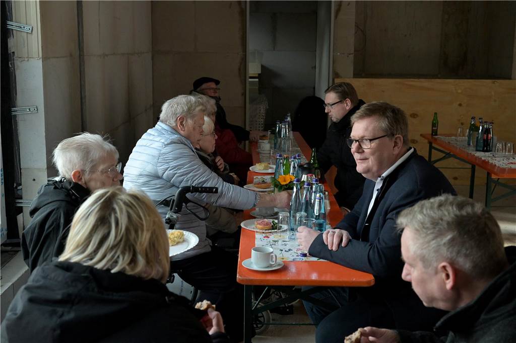 Viele Gäste am Tisch im Rohbau.