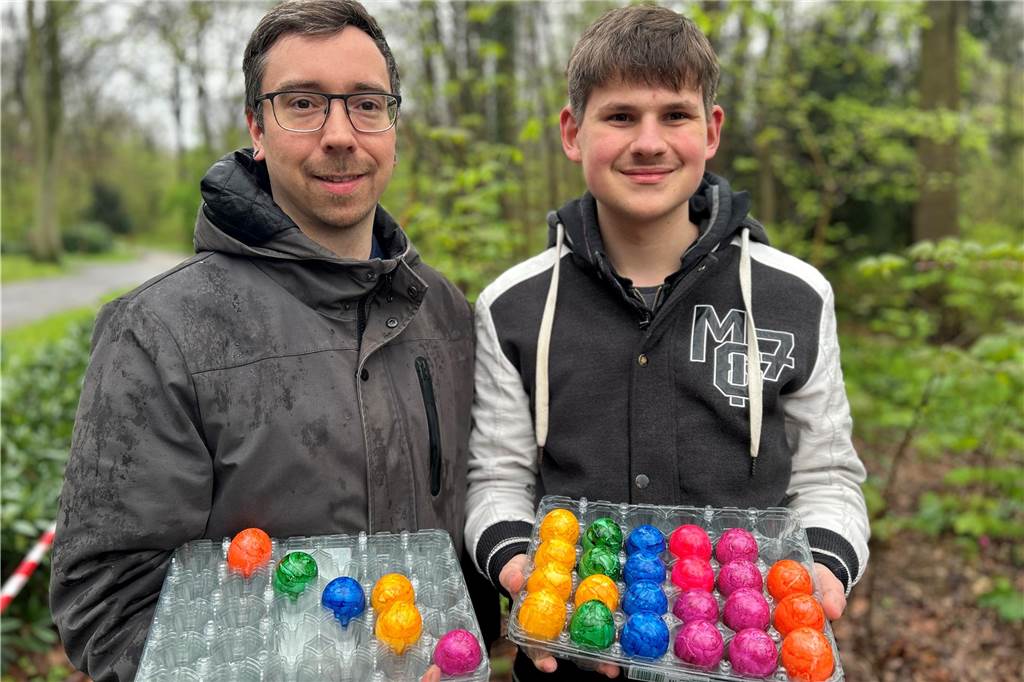 Zwei Männer, die Paletten bunte gekochte Eier halten.