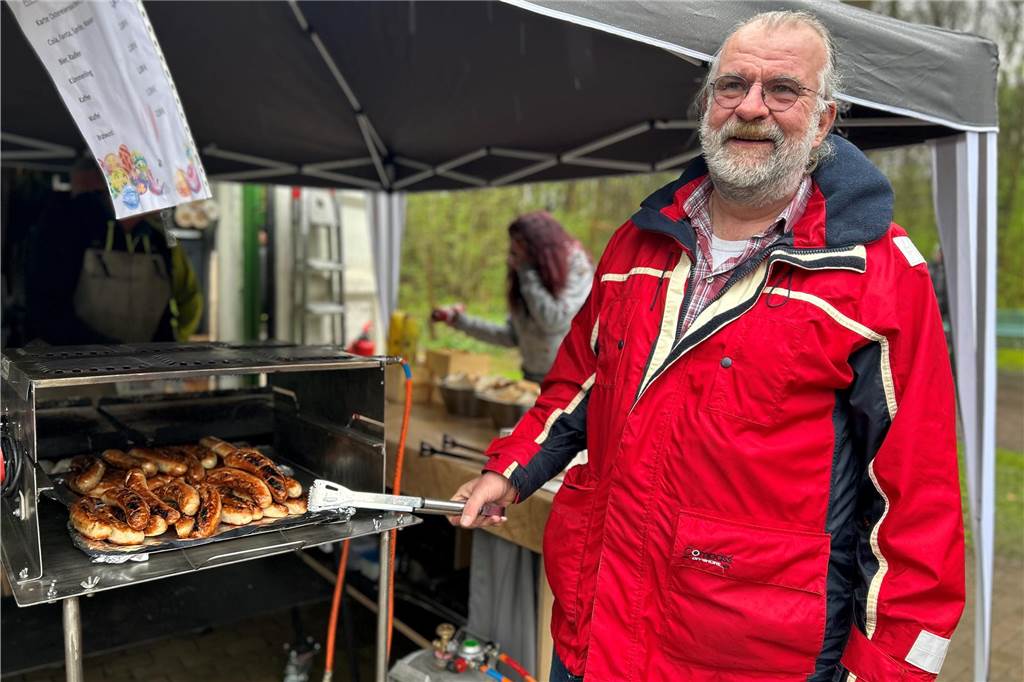 Ein Mann, der Bratwürste am Grill brät.