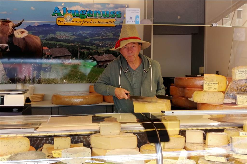 Markthändler Detlef Bothor-Oberstadt steht in seinem Käsewagen und schneidet ein Stück Käse.