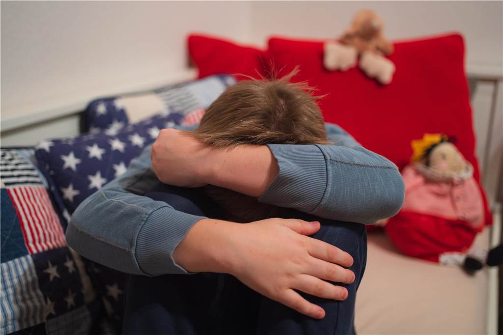„Keine Insel der Glückseligen“: Stadt baut den Kinderschutz massiv aus Ein Kind verschränkt seine Arme vor seinem Kopf.