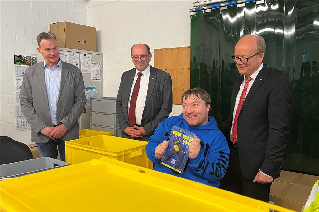 Voller Stolz zeigt ein Beschäftigter der Werkstätten den Gästen sein fertig verpacktes Produkt: Eine Abisolierzange.