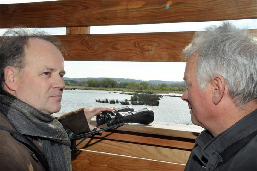 In Westhofen: Neue Nisthilfe für Störche gebaut Vom Beobachtungsstand an der gefluteten Röllingswiese nehmen Wolfgang Pitzer (l.) und Michael Müller (r.) den neuen Storchenmast ins Visier, den sie geschützt am anderen Ufer der Wasserfläche als Nisthilfe aufgestellt haben.