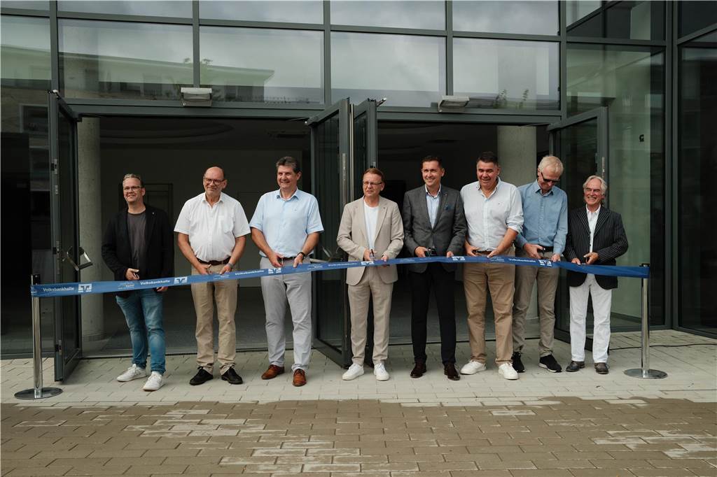 Eröffnung des Burgerladens „Kunstwerk“: Auch Name der Dreifachturnhalle steht Männer schneiden mit einer Schere ein blauer Eröffnungsband durch.