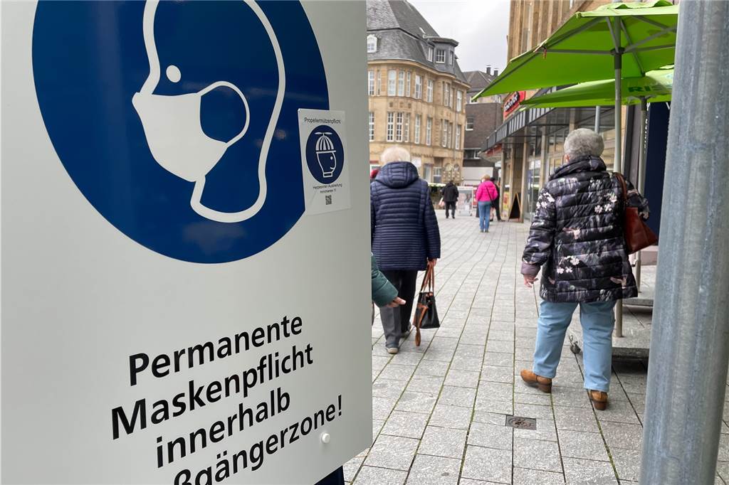 Corona: Sonderbare Aufkleber sorgen in Castrop-Rauxel für Aufregung Vor Blumen Risse steht ein Schild, das den Aufkleber trägt.