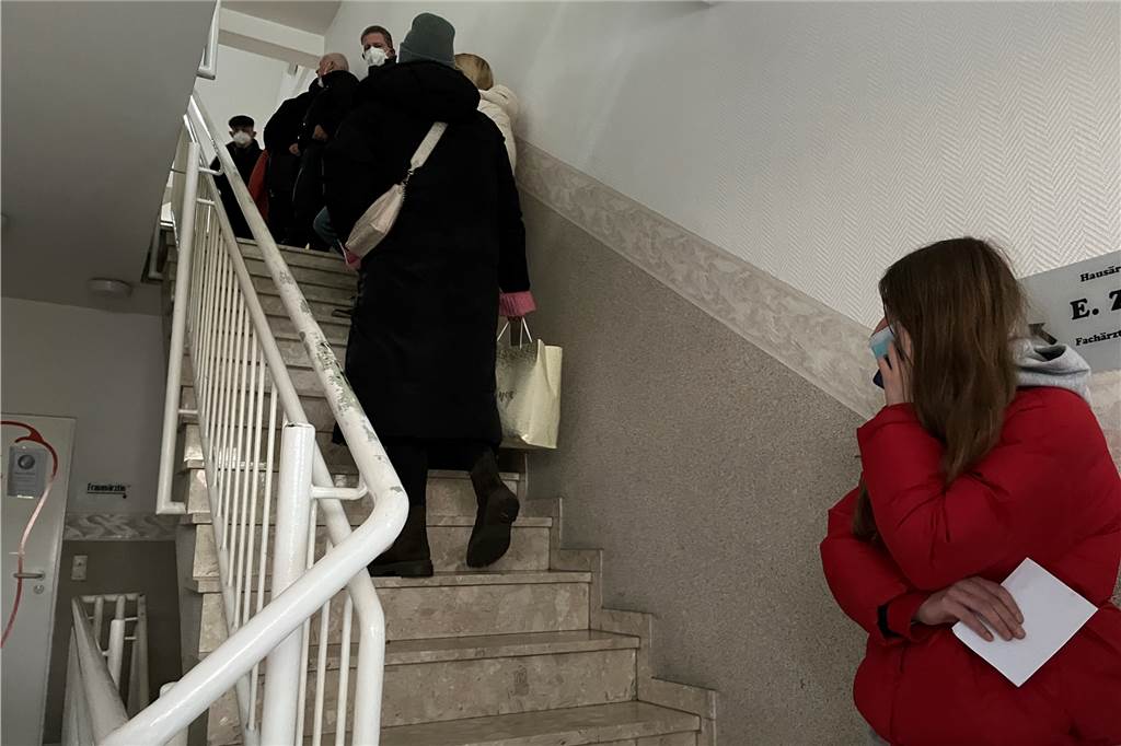 Lange Schlange und enttäuschte Patienten vor Praxis von Ewa Zielinski Menschen stehen auf einer Treppe Schlange.