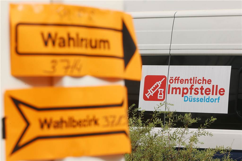 Bundestagswahl: Laschet in der Kritik, Grüne und FDP in Sondierungen - wird Habeck Vizekanzler? Vor einem Wahllokal in einer Schule und neben einer mobilen Impfstation für Covid-19-Impfungen weisen zwei gelbe Zettel den Wählern den Weg.