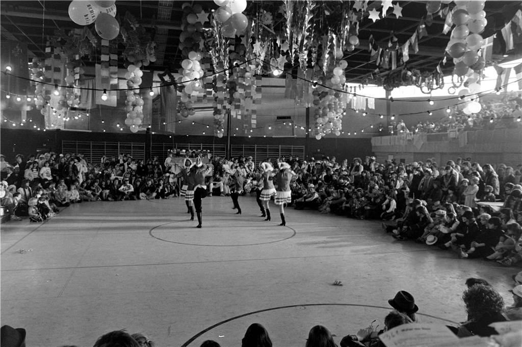 Menschen feiern Karneval in einer Sporthalle.