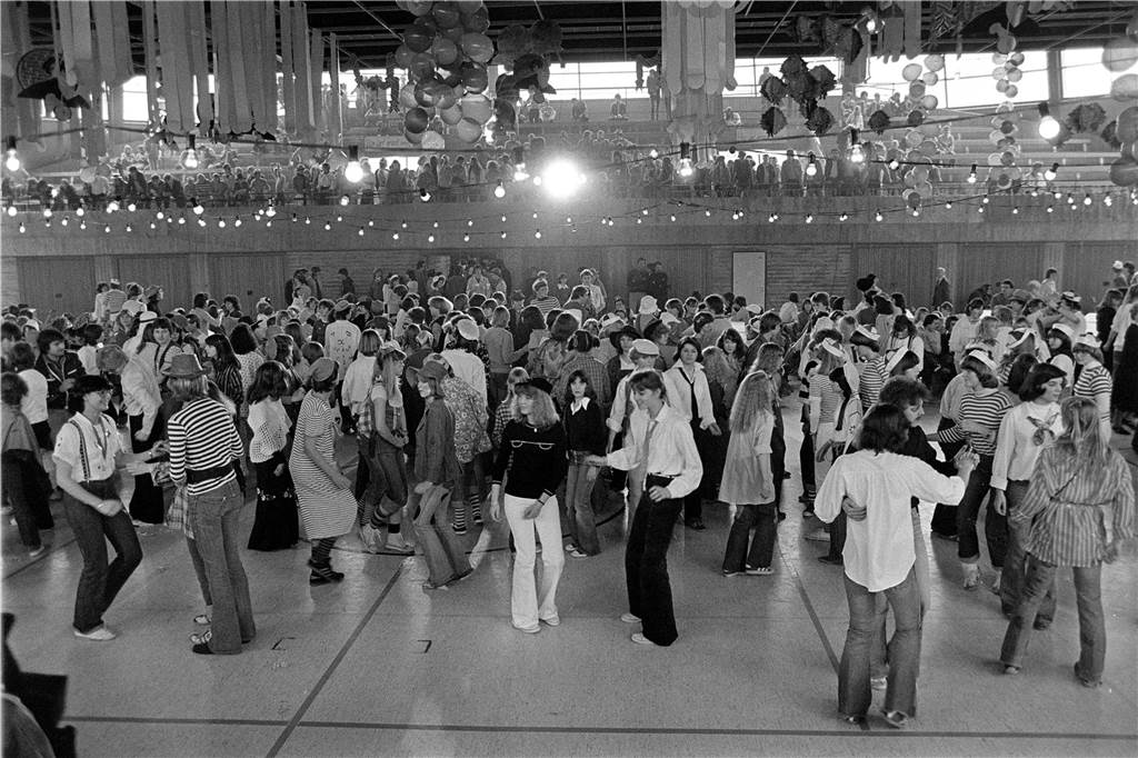 Menschen tanzen in einer Turnhalle.