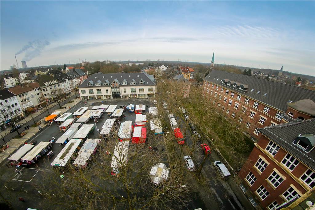Blick auf den Mengeder Markt mit Wochenmarktständen, Geschäftshäusern und der Jeanette-Wolff-Hauptschule