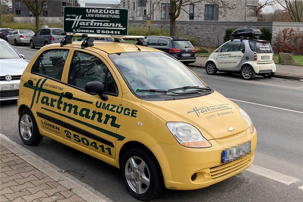 Dürfen die das? Werbefahrzeuge blockieren Parkplätze in Lünen Während das Fahrzeug im Vordergrund spezielle Werbetafeln auf dem Dachgepäckträger montiert hat, hat das Werbefahrzeug im Hintergrund eine Dachbox installiert, die ebenfalls mit Werbung bedruckt ist. Das ergibt sogar Sinn: Denn die Firma vermietet eben diese Dachboxen.
