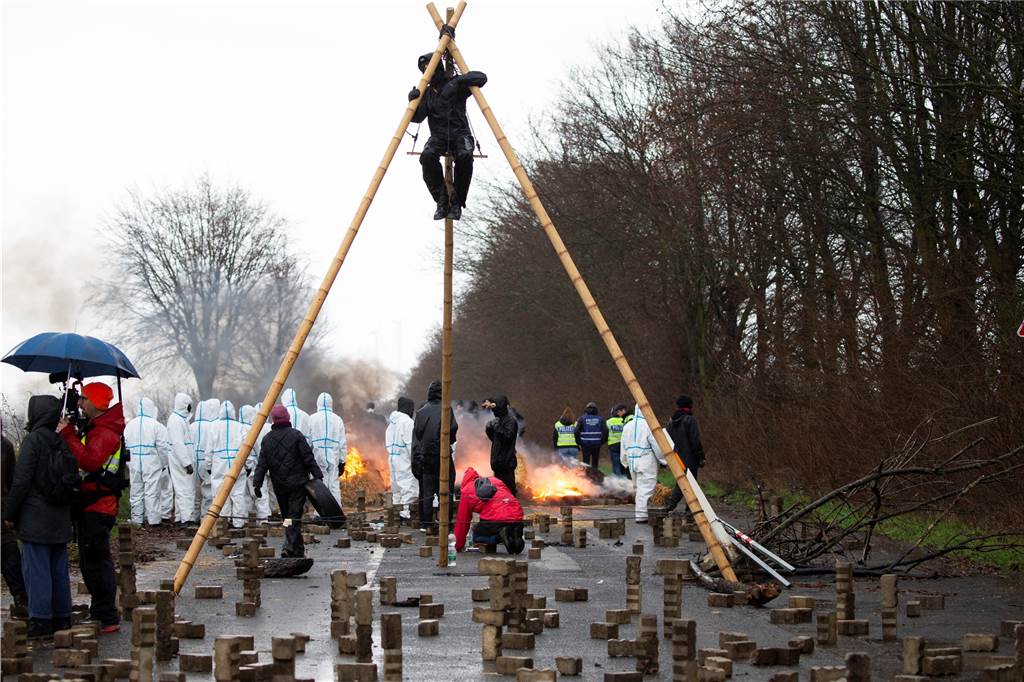 Räumung von Braunkohledorf Lützerath: Luisa Neubauer ruft zum Widerstand auf - „Jeder Tag zählt“ Aktivisten in weißen Overalls bauen Steine und Holz als Barrikaden auf.