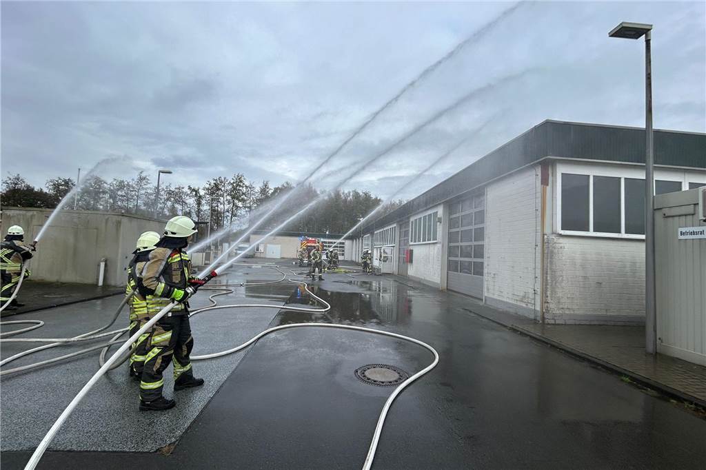 Feuerwehrleute richten ihre Wasserstrahlen auf den simulierten Brand
