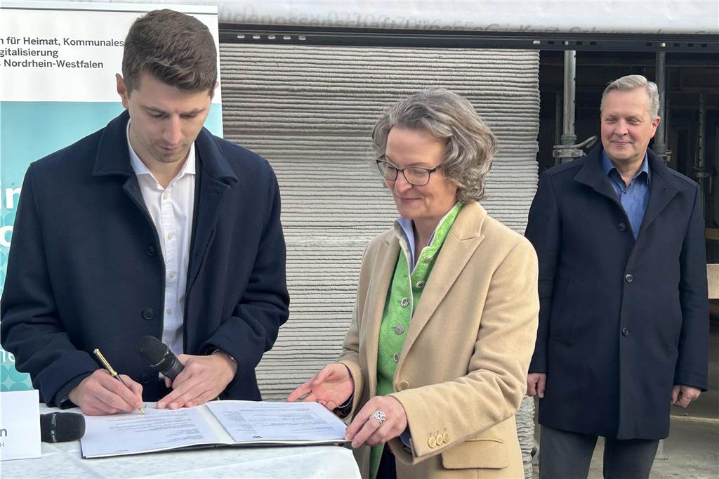 Bezahlbares Wohnen aus 3D-Drucker: Bürgermeister lobt Pionierarbeit WBG-Vorstand Jan Hische (l.) unterzeichnet die Förderurkunde im Beisein von NRW-Bauministerin Ina Scharrenbach und Bürgermeister Jürgen Kleine-Frauns.