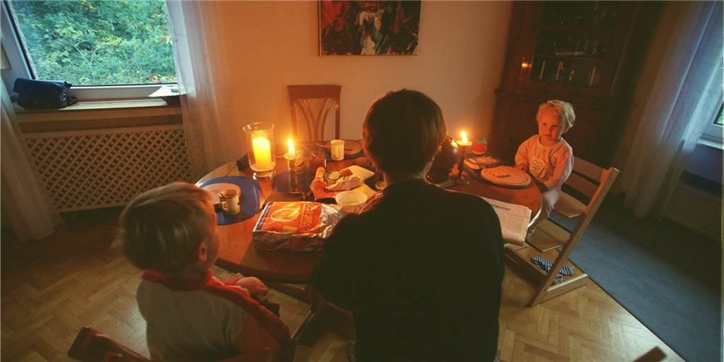 Möglicher Blackout: Wie gut ist Dortmund vorbereitet? Eine Familie sitzt bei Kerzenlicht am Tisch.