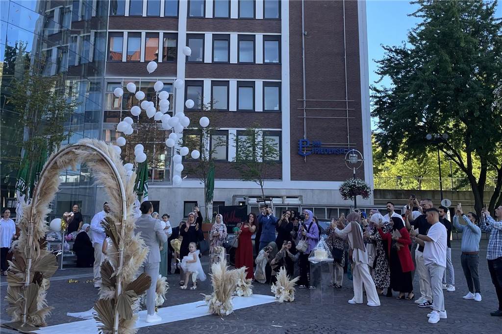Erst Jogginghose, jetzt schickes Kleid: Emirhan und Isil haben geheiratet Weiße kleine Ballons fliegen in die Luft. Das Brautpaar und die Hochzeitsgäste schauen ihnen hinterher.