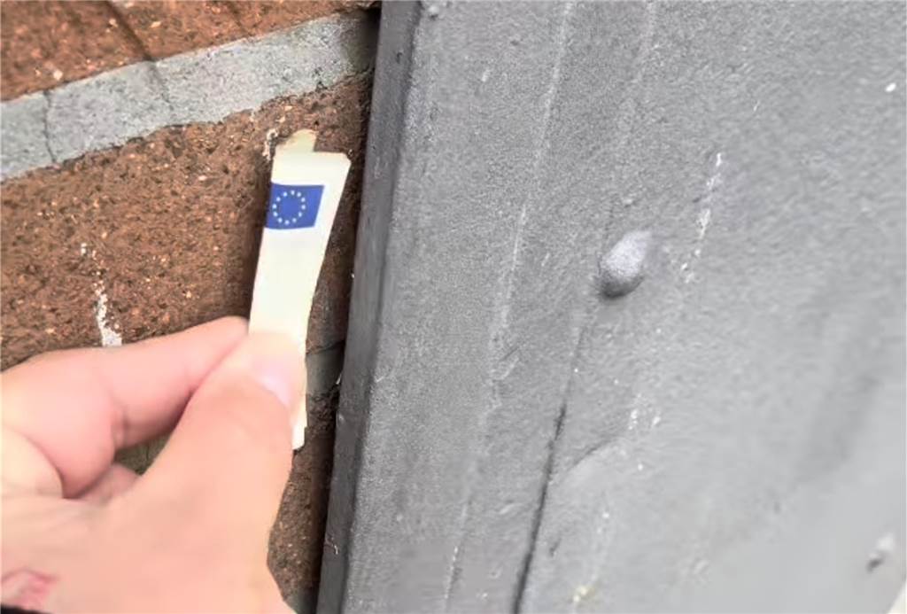 Verstecktes Geld in der Stadt soll Menschen Freude bereiten Dennis steckt einen 5 Euro Schein in einen schmalen Spalt an der Wand.
