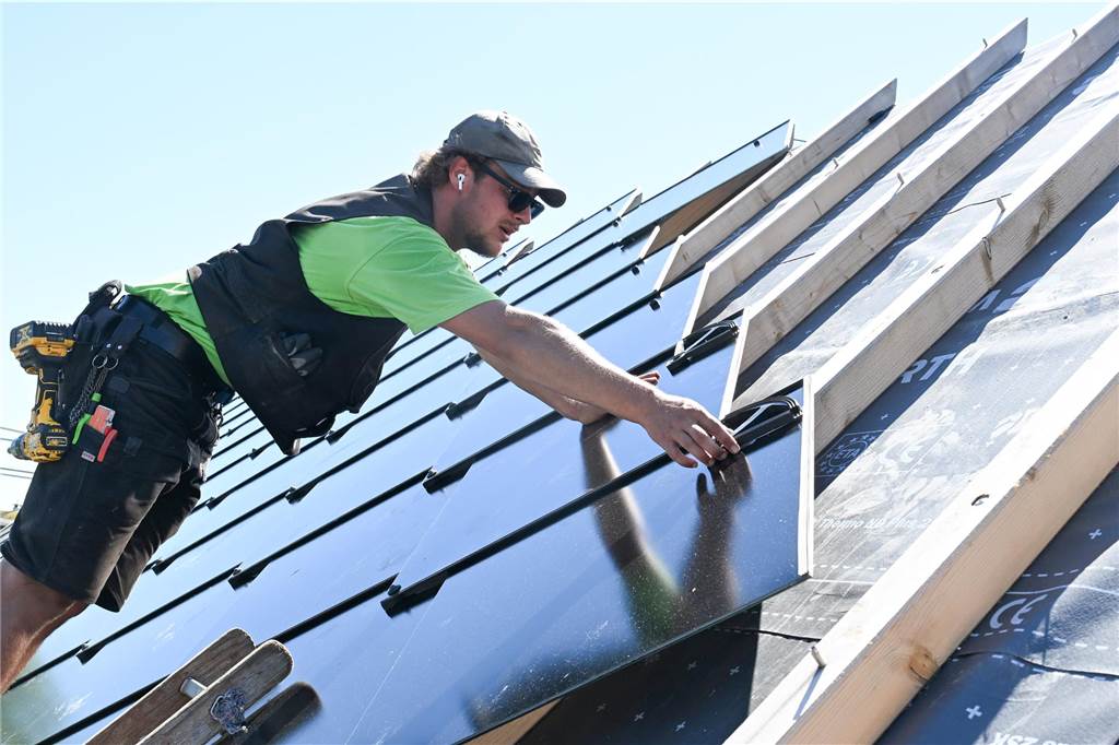 Kaufen oder doch lieber mieten? : Experte informiert online über Photovoltaikanlagen Ein Handwerker installiert eine Photovoltaik-Anlage auf einem Dach.