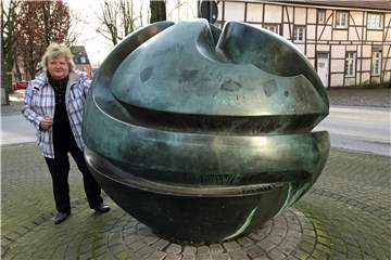 Wernes Stadtführerin Heidelore Fertig-Möller zeigt die Bronzekugel auf dem Domhof-Parkplatz an der Südmauer in Werne.