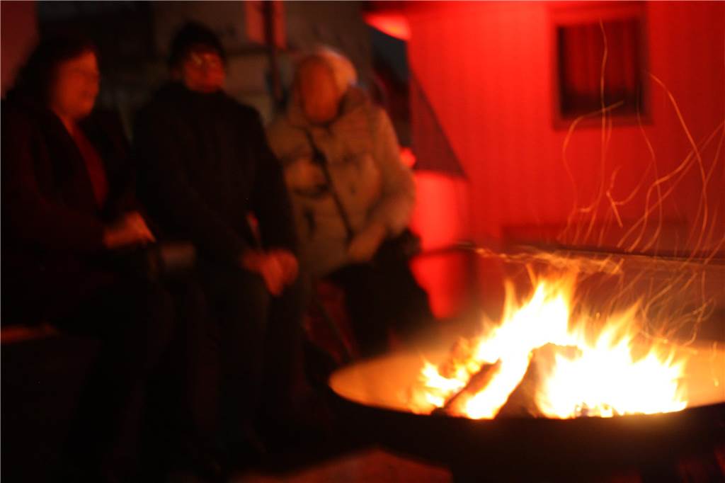 Besucher sitzen um ein Lagerfeuer bei der „Nacht der Lichter“ in Dortmund-Hörde.