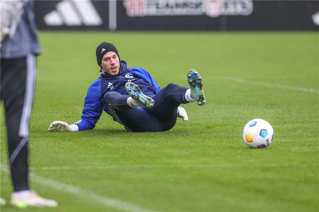 Torwart Marius Müller sitzt beim Training des FC Schalke 04 auf dem Rasen.
