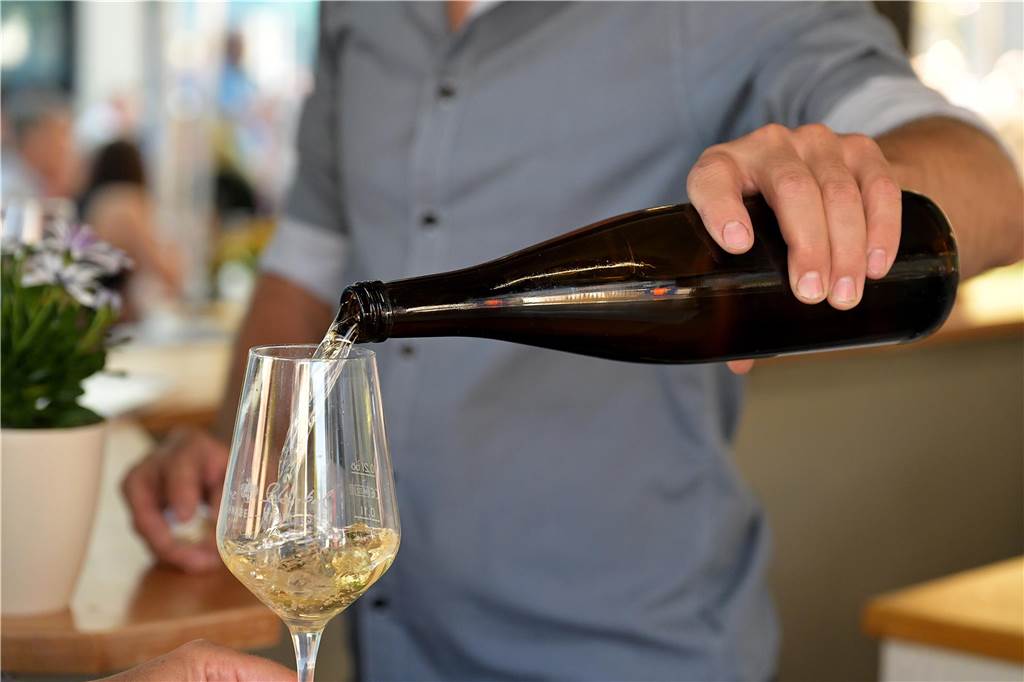 Ein Winzer gießt beim Weinfest in Lünen Weißwein in ein Glas.