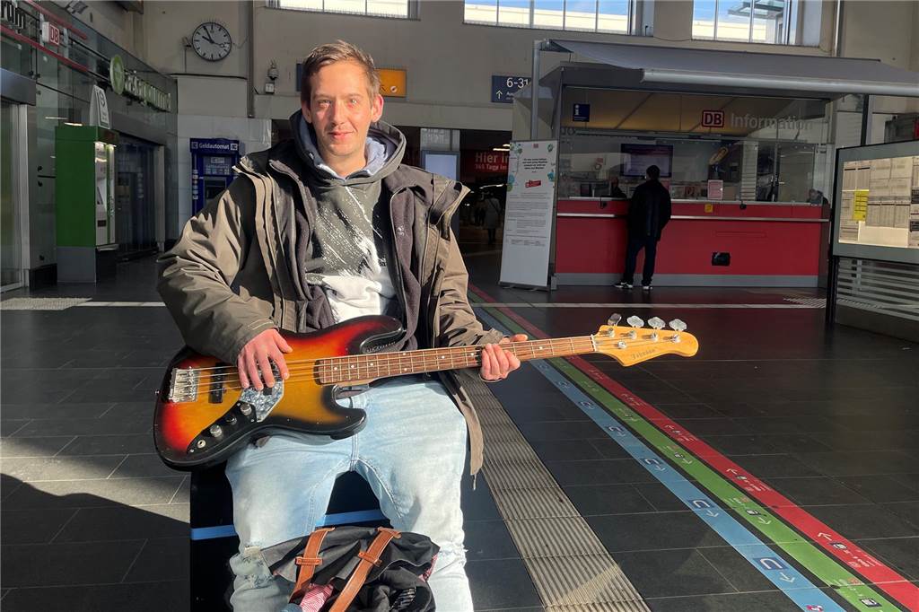 Dortmund erlebt größten Warnstreik seit langer Zeit Yannick Meehsen sitzt mit einem E-Bass auf dem Schoss auf einem Verstärker in der Haupthalle des Dortmunder Hauptbahnhofs.