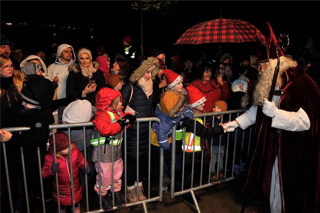 Auf dem Foto sind zahlreiche Kinder zu sehen, die hinter einer Absperrung den Nikolaus begrüßen.