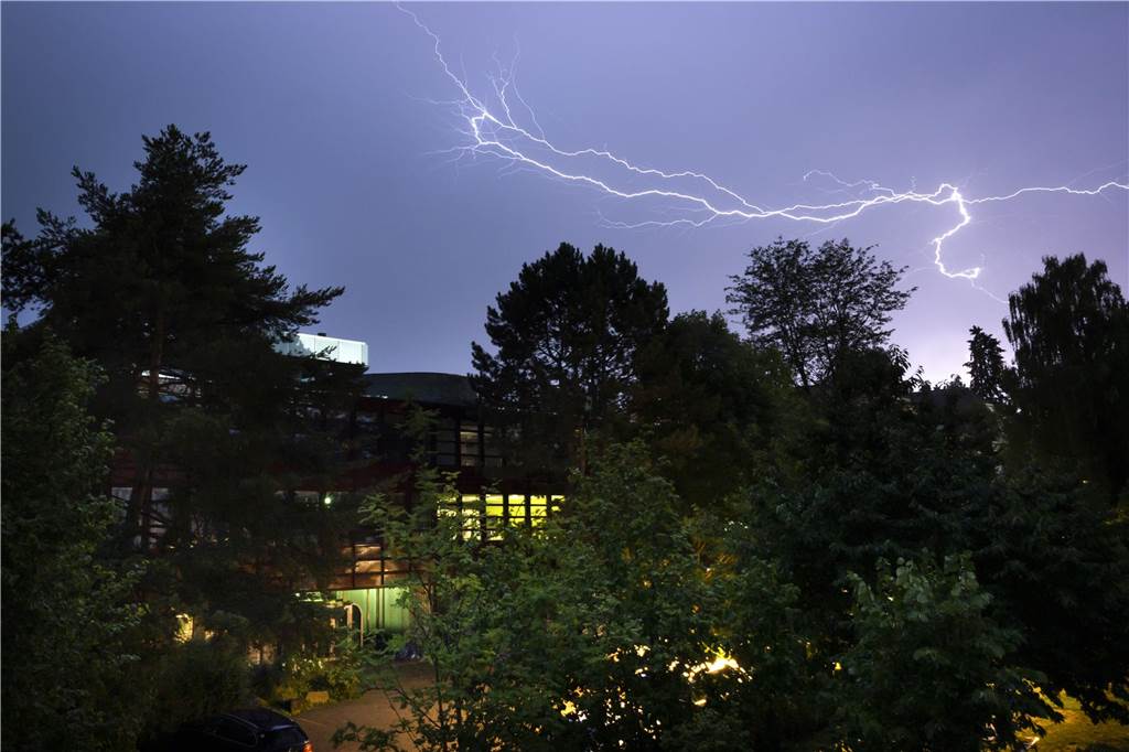Unwetter im Westen und Süden Deutschlands: Katastrophenschutz geht von Tornado aus Ein Blitz ist während eines Gewitters über einem Schulhaus eines Freien Gymnasiums zu sehen.