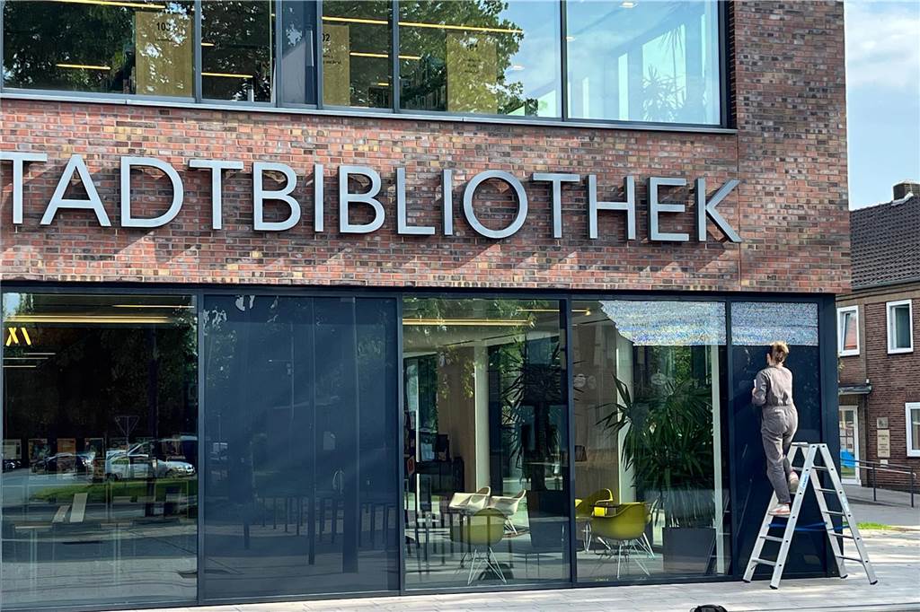 Vera Vorneweg schreibt Handschrift auf die Fassade der Stadtbibliothek Zeile für Zeile fügt Vera Vorneweg ihren Text handschriftlich auf den großen Fenstern der Stadtbibliothek zusammen. Er soll Passanten innehalten lassen. Für die Künstlerin ist es das erste Mal, dass sie auf Glas und auf einem intakten Gebäude schreibt.