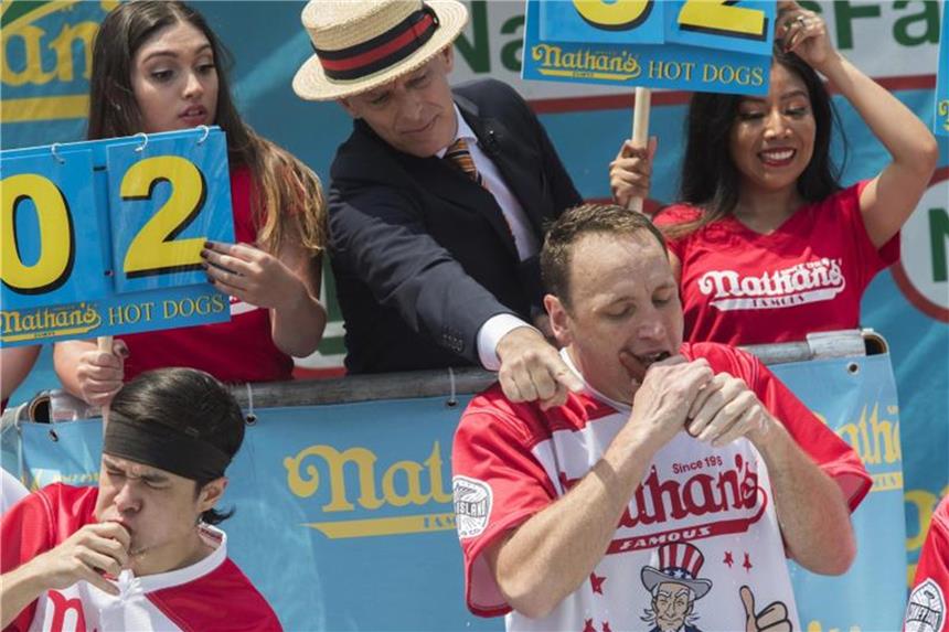 Hotdog-Wettessen: 74 Würstchen in zehn Minuten Zeremonienmeister George Shea (Mitte oben), verkündet den Sieg von Joey Chestnut (rechts unten). Foto: Mary Altaffer/AP