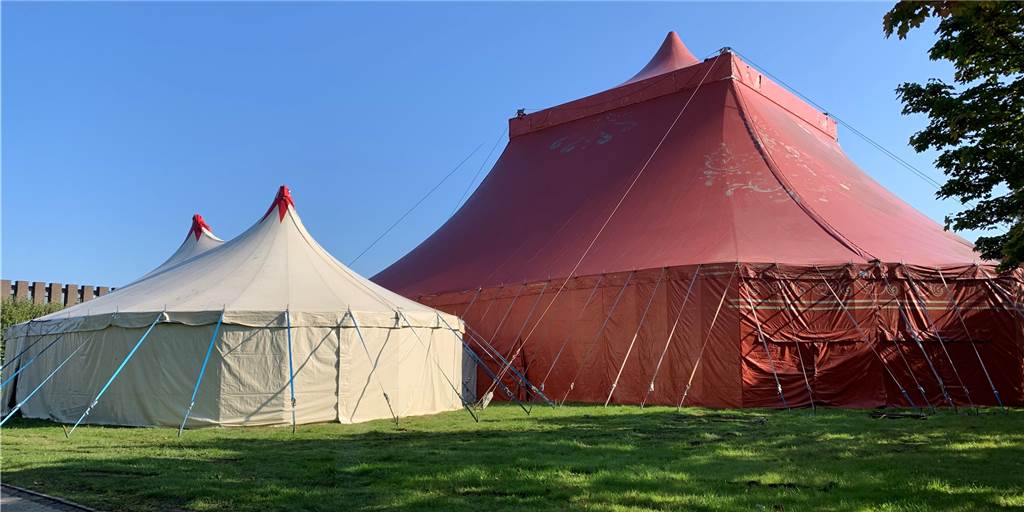 Rotes Zirkuszelt auf dem Europaplatz kommt nächste Woche zum Einsatz Auf der Wiese neben der Europahalle steht ein rotes Zirkuszelt sowie ein kleineres weißes Vorzelt.