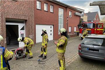 Feuerwehrmänner stehen mit einem Lüfter vor einem Haus an der Klümperstraße in Raesfeld.