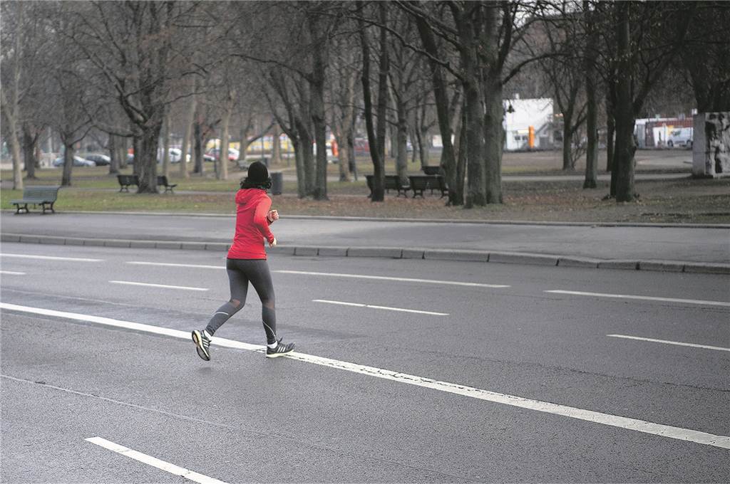 Von links laufen bis spucken: Was Jogger dürfen oder lieber lassen sollten Zügig und auf dem kürzesten Weg: Eine Joggerin überquert eine Straße, auf der gerade kein Verkehr ist.