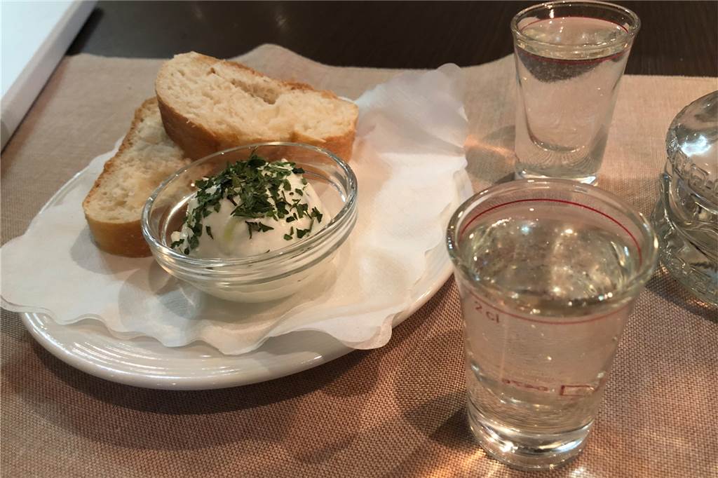 Warum können griechische Restaurants nicht so wie in Griechenland sein? Zum Auftakt werden ungefragt als kleiner Gruß ein Ouzo und eine zazikiähnliche Frischkäsecreme serviert.
