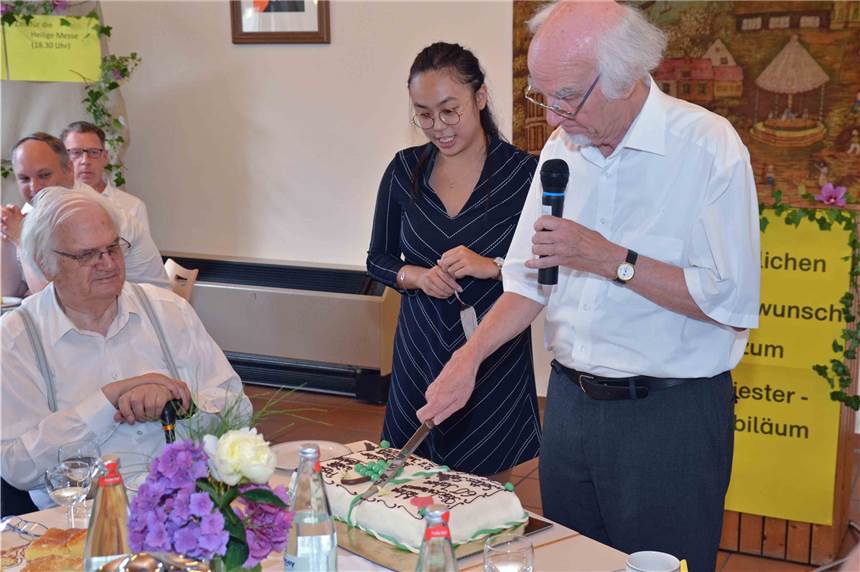 Zum Diamantenen Priesterjubiläum von Pfarrer i.R. Willi Aufenberg (r.) freute er sich über eine verzierte Buttercremetorte, die Mandy Huynh (M.) mit ihrer Familie gebacken hatte, um ihrem Pfarrer mit Herz danke zu sagen.