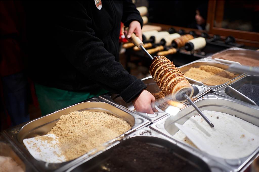 Die 5 außergewöhnlichsten Essensbuden auf dem Weihnachtsmarkt Zum Schluss werden die karamellisierten Baumstriezel hier mit gebrannten Mandelstückchen bestreut.