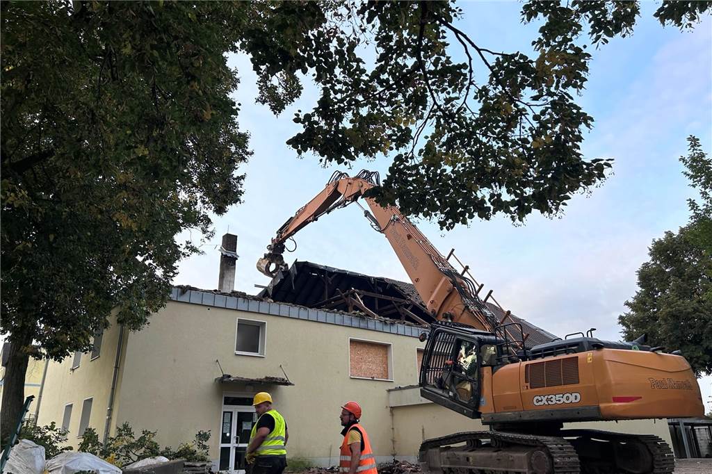 Zum Start der Sanierung trägt ein großer Bagger den vom Brand zerstörten Dachstuhl der Turnhalle ab.