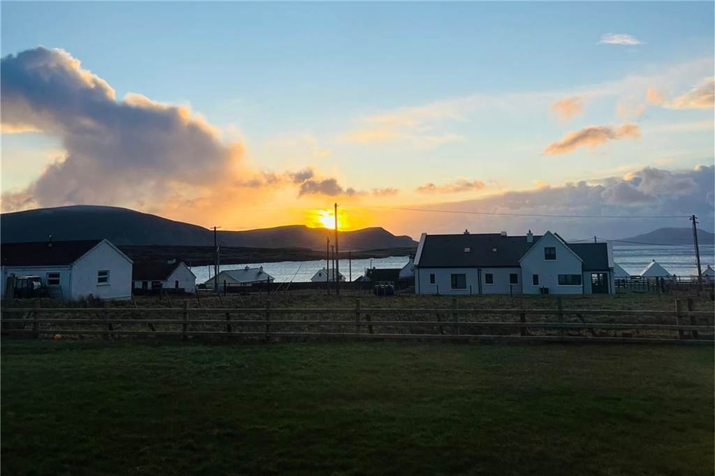 So erlebt Mareike Graepel den Sturm Éowyn in Irland Ein paar Häuser vor tiefstehender Sonne an der Küste Irlands.