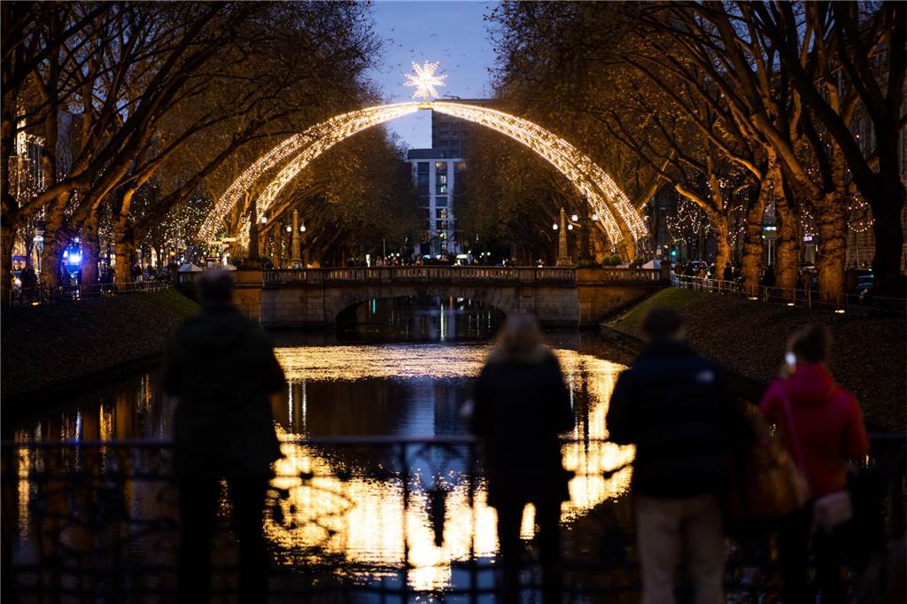Weihnachtsmarkt Düsseldorf 2023: Öffnungszeiten, Standorte - Infos für Besucher Passanten betrachten während des Weihnachtsmarktes in Düsseldorf die Lichter-Deko an der Königsallee.
