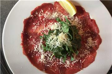 Zur Vorspeise gibt es bei Prima Fila Rindercarpaccio mit Rukola und Parmesan.