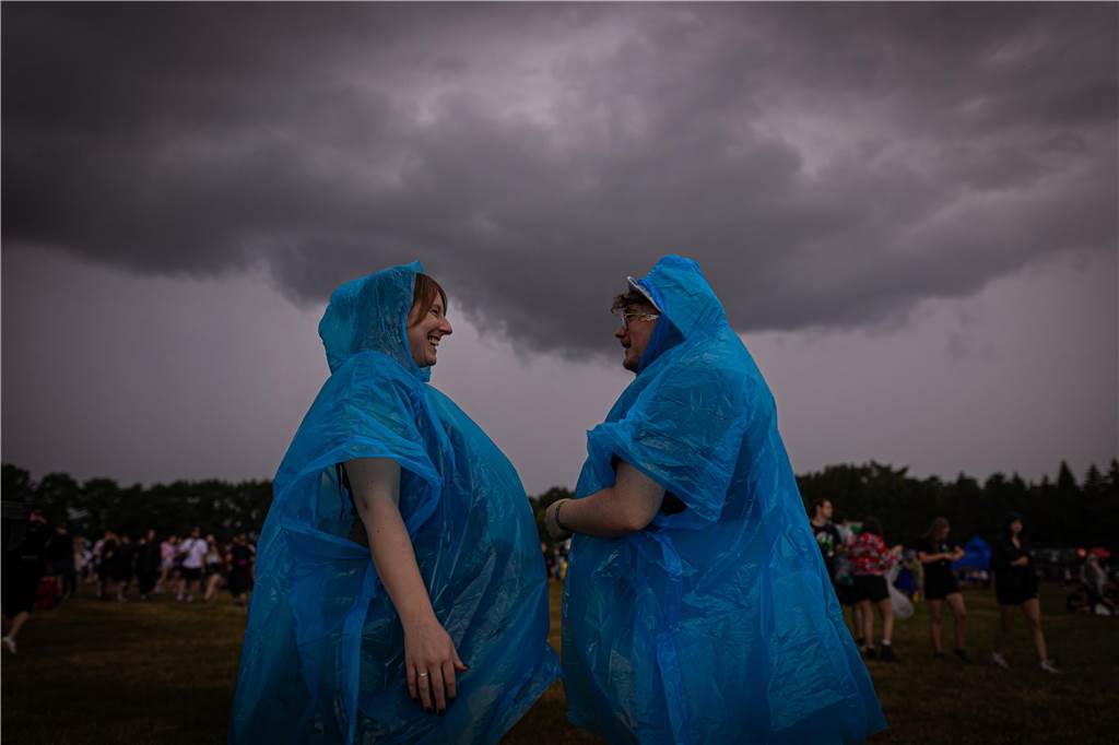 Unwetter über Deutschland: EM-Fanzonen geschlossen und Hurricane-Festival unterbrochen Zwei Festivalbesucher tragen Regenponchos, während dunkle Regenwolken über das Gelände des Hurricane Festivals hinwegziehen. Das Open-Air-Festival findet vom 21. bis zum 23.06. statt.