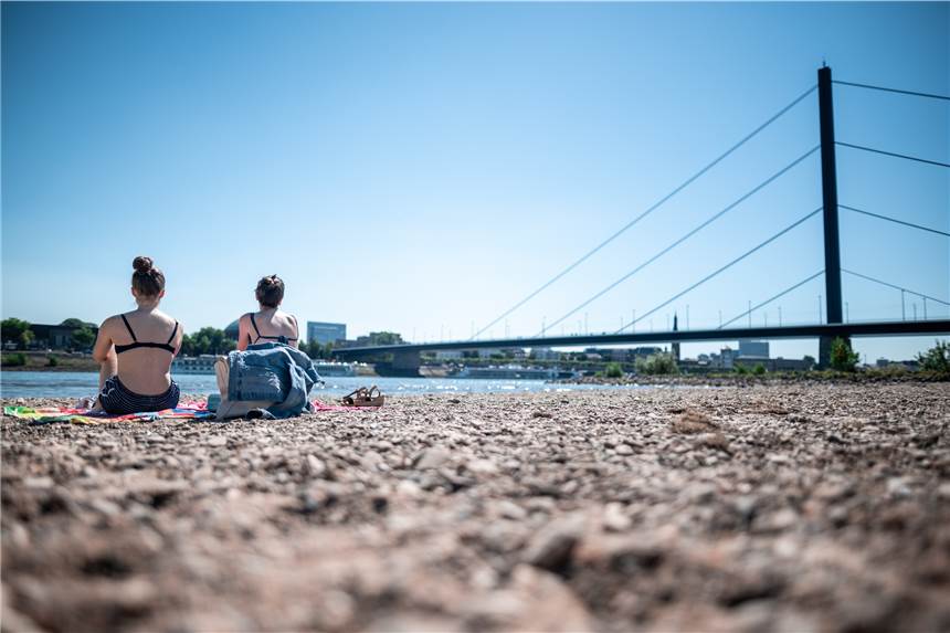 Mit 37,4 Grad der bislang heißeste Tag des Jahres in NRW erreicht Zwei Frauen sitzen mit einen Handtuch am Rhein in Düsseldorf. Nordrhein-Westfalen steuert auf einen neuen Jahres-Hitzerekord zu.