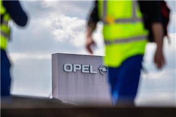 Zwei Männer in Sicherheitswesten gehen am Stammwerk von Opel in Rüsselsheim vorbei. Foto: Andreas Arnold